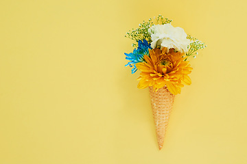 Image showing Flowers ice cream in a cone in studio for creative, art or decoration with fresh and colorful bouquet. Creativity, still life and floral plants in a dessert isolated by yellow background with mockup.