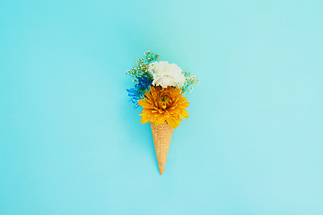 Image showing Floral, ice cream and cone in studio for creativity, art or decoration with fresh and colorful bouquet. Creative, still life and flower plants in dessert isolated by blue background with mockup space