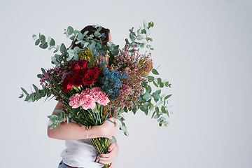 Image showing Natural, gift and woman with flowers, spring and eco friendly against grey background. Female person, model and girl with a floral present, bouquet or hide face with sustainability, nature and plants