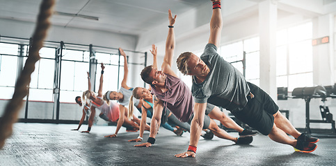Image showing Fitness class, group and people doing a workout in the gym for health, wellness and flexibility. Sports, training and athletes doing a side plank exercise challenge together in sport studio or center