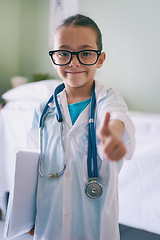 Image showing Girl child, playing and doctor thumbs up in portrait with smile, glasses and stethoscope in hospital. Female kid, play medic and happy with excited face, learning and hand sign for yes emoji in house