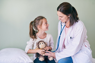 Image showing Medical, kids and a girl at a woman pediatrician for an appointment or checkup in the hospital. Healthcare, stethoscope and teddy bear with an adorable female child sitting on a bed in the clinic