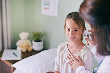 Image showing Healthcare, portrait and a girl at the pediatrician for an ear checkup or appointment in the hospital. Medical, kids and health with an adorable little female child sitting on a bed in the clinic