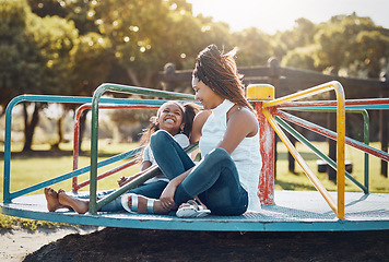 Image showing Woman, young girl together on roundabout at park and playing with smile and fun outdoor. Love, care and bonding with family happiness, mother and daughter enjoying time at playground with freedom