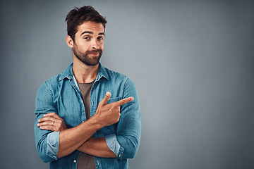 Image showing Portrait, pointing and man with mockup, promotion and opportunity against a grey studio background. Face, male person and model with casual outfit, decision and choice with happiness and showing