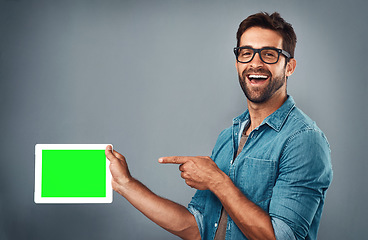 Image showing Happy man, tablet and pointing on mockup green screen for advertising against a grey studio background. Portrait of male person with smile showing technology display, chromakey or copy space branding