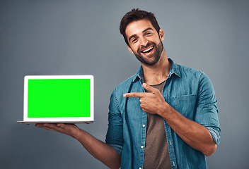 Image showing Happy man, tablet and pointing to green screen for advertising against a grey studio background. Portrait of male person smiling and showing technology display, chromakey or mockup for advertisement