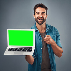 Image showing Happy man, laptop and pointing with green screen in advertising or marketing against a grey studio background. Portrait of male person showing computer display, mockup or copy space for advertisement