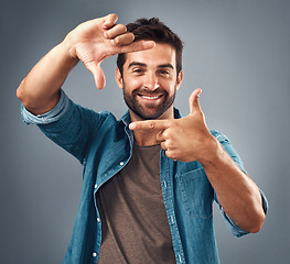 Image showing Frame, face and portrait of man in studio on gray background with happiness, confident and smile. Finger border, fashion and happy male person with hand sign for picture, photography and perspective