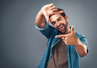 Image showing Frame, excited and portrait of man in studio on gray background with happiness, confident and smile. Finger border, face and happy male person with hand sign for picture, photography and perspective