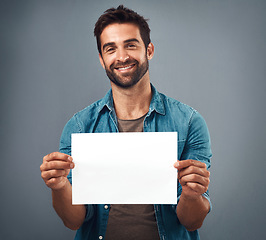 Image showing Happy man, portrait and billboard on mockup for advertising, marketing or branding against a grey studio background. Male person holding rectangle poster or placard for sign, message or advertisement