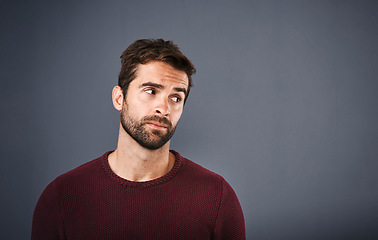 Image showing Doubt, thinking and face of unsure man in studio with worry, uncertain and thoughtful on gray background. Confused, mockup space and isolated male person skeptical for decision, choice and question