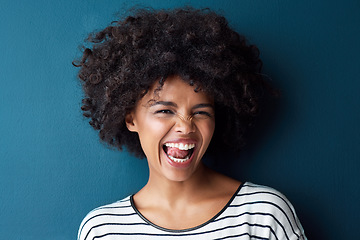 Image showing Portrait, funny and woman with tongue out, silly and happiness against a blue studio background. Face, female person and model with facial expression, humor and comic with joy, smile and goofy girl