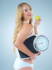 Image showing Woman is eating apple, smile with scale and lose weight, portrait and healthy food isolated on studio background. Happy female model, health and diet with organic fruit with nutrition and weightloss