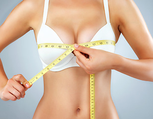 Image showing Woman, hands and breast with measuring tape, bust size with body and lose weight isolated on studio background. Female person in underwear, bra and chest measurement, health and diet for weightloss