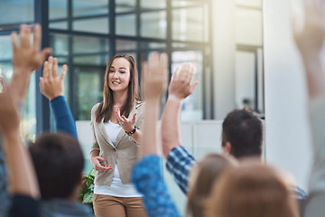 Image showing Woman speaker at seminar, audience with hands up for questions and answers at training presentation or meeting. Feedback, opinion and ideas, group of people at conference, hand in air and question.