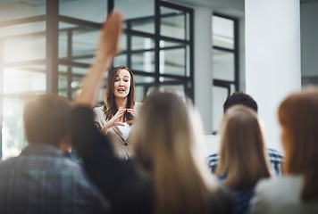 Image showing Woman speaker at seminar, audience with hands up for questions and answers at training presentation or meeting. Feedback, opinion and ideas, group of people at conference, hand in air and question.