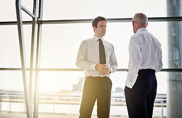 Image showing Collaboration, window and flare with business men in discussion while standing in their corporate office. Meeting, teamwork and planning with a corporate employee chatting to a colleague at work