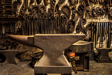 Image showing Workshop, metal tools and anvil in forge with wall background for industry, manufacturing or development. Retro factory, workspace or industrial for steel, iron or product with vintage craftsmanship