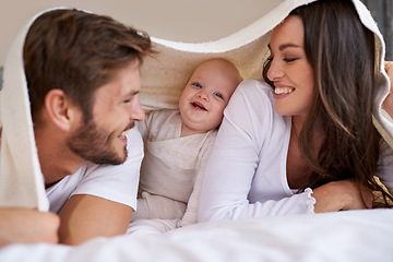 Image showing Happy mother, father and baby with blanket on bed for love, care and quality time together. Parents, family and playful newborn child relaxing in bedroom with bedding fort, smile and bonding at home