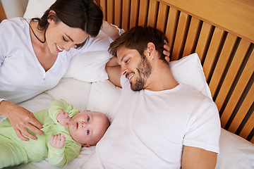 Image showing Above of mother, father and baby in bedroom for love, care and quality time together at home. Happy parents, family and newborn kid relax on bed with support, childhood development and fun bonding