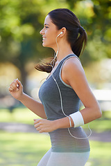 Image showing Sports, earphones and athlete running in a park for health, wellness and outdoor exercise. Nature, fitness and female runner doing cardio workout in garden listening to music or radio and training.