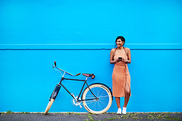 Image showing Bicycle, young woman with smartphone and happy outside by blue wall. Cycling in urban area, health wellness and female person on cellphone outdoors standing in streets with bike or cycle in road
