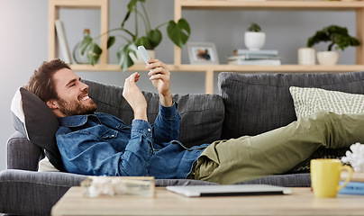 Image showing Social networking, man with smartphone on sofa and lying in living room at his home. Connectivity or technology, smile and happy male person with cellphone comfortable on couch playing online game