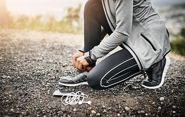 Image showing Closeup, headphones and woman tie shoes, fitness and healthy with runner outdoor, wellness and training. Female person, athlete and girl with technology, hands and practice to start running and laces