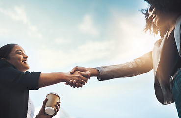 Image showing Business people, handshake and meeting below for greeting, introduction or partnership with sky background. Happy women shaking hands for b2b, collaboration or teamwork and agreement in deal outdoors