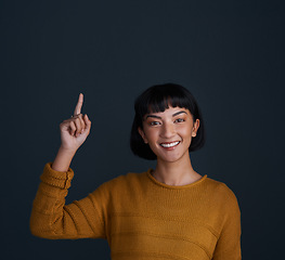 Image showing Woman is pointing up, marketing and mockup space with portrait, smile and promo isolated on blue background. Young female person, happy ambassador and branding with advertising and show in studio