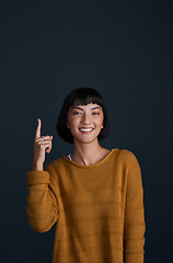 Image showing Woman in portrait, pointing up with advertising and mockup space, smile and promo isolated on dark background. Happy female person, ambassador and branding with marketing and presentation in studio