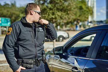 Image showing Police, radio and security with a man officer outdoor on patrol while talking to headquarters for a situation report. Law, safety and communication with a policeman on the street for justice