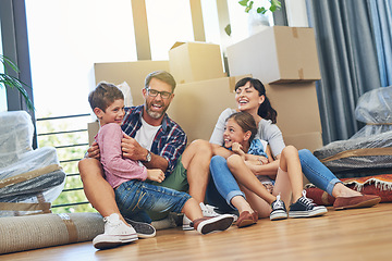 Image showing Children, parents and laughing in apartment with box on living room floor with happiness for lifestyle. Family, boxes and excited in new house with investment in a mortgage for saving and wealth.