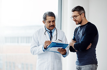 Image showing Healthcare, documents and a doctor with a man patient in the hospital talking during a consulting checkup. Medical, health and wellness with a medicine professional speaking to a client in a clinic