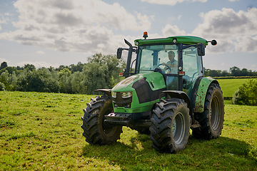 Image showing Man, farm and green tractor on grass in countryside for agriculture, lawn or sustainability in nature. Male person or farmer in big agricultural machinery for farming, ecology or construction on land