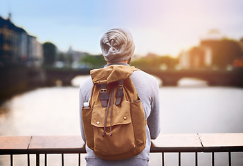 Image showing Back, travel and a tourist man by a lake in the city for adventure or a journey of self discovery abroad. Bridge, view and blurred background with a male traveler standing outside in an urban town