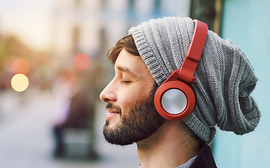 Image showing Relax, smile and man with headphones for music, radio or a podcast in the city. Happy, freedom and a young person sitting, enjoying and listening to audio, calm songs or zen sound while downtown