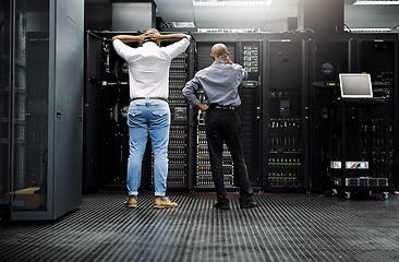 Image showing Server room, it support or electrician fixing a problem for hardware maintenance or stressful glitch crisis. Confused or back of worried technicians or electrical engineers in information technology