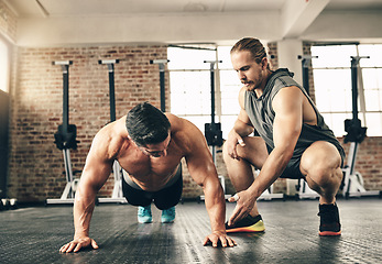 Image showing Man, coach and motivation for pushup on gym floor for fitness, health and building muscle for sport. Personal trainer, bodybuilder men and workout with advice, helping hand and together for support