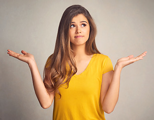 Image showing Thinking, doubt and shrug with a woman in studio on a gray background looking confused by her options. Idea, question and hand gesture with an attractive young female person weighing up a decision