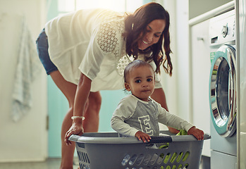 Image showing Cleaning, mother and baby playing in basket doing the laundry in their home. Hygiene or clean for wellness, positive and happy family have fun bonding together at washing machine with lens flare