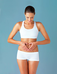 Image showing Heart, hands on abdomen and woman with gut health and wellness isolated on blue background. Weight loss, fitness and healthy female person with self love and body care in studio with diet