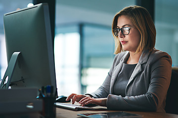 Image showing Computer, business woman and typing in office, working late on project and focus at night. Desktop, professional and female person writing email, report or planning, reading and overtime for deadline