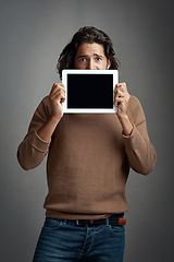 Image showing Tablet screen, mockup and portrait of man peeking in studio isolated on a gray background. Touchscreen, scared and male person with space for marketing, advertising and technology for promotion.