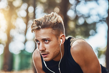 Image showing Man with earphones, breathing after running in forest and fitness with music, listening for motivation on run in park. Male runner outdoor, rest with podcast or radio streaming, exercise and cardio