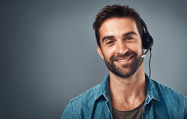 Image showing Happy man, call center and headphones for consulting on mockup space against a grey studio background. Portrait of friendly male consultant agent with smile and headset in contact us or online advice