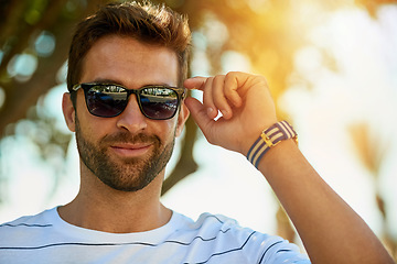 Image showing Happy, sunglasses and portrait of a man in an outdoor park while on a summer vacation, adventure or holiday. Smile, confidence and young male person with eyewear standing in a garden on weekend trip.