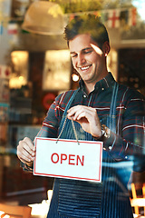 Image showing Open sign, smile and man with business, startup success and service with restaurant, window and coffee shop. Male person, employee and entrepreneur with billboard, poster and opening retail store