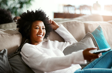 Image showing Black woman, watching tv and relax on sofa with remote, smile and happiness for film, comedy or show. African girl, television and happy for movie, video and browsing on lounge couch in apartment